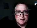 Mężczyzna z niebieskimi oczami i okularami. Jego **czerwona twarz** emanuje ciepłem, a na policzkach widać rumieńce.