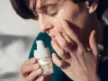 Twarz 50 latki z aplikacją kremu pod oczy. Dłonie delikatnie rozprowadzają produkt, dbając o skórę.