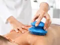Masaż bańką chińską: terapeuta wykonuje zabieg na plecach pacjenta. Choć zazwyczaj przynosi ulgę, warto znać potencjalne masaż bańką chińską efekty uboczne.