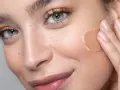 Delikatna aplikacja kremu BB lub podkładu na piegowaną cerę, podkreślająca naturalne piękno.