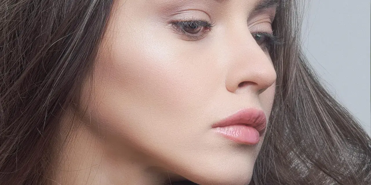 Delikatny makijaż glow podkreślający naturalne piękno. Skóra promienieje subtelnym blaskiem, a usta są muśnięte różowym błyszczykiem.