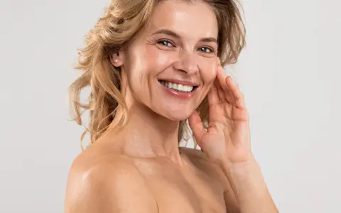 Uśmiechnięta kobieta z blond włosami, która odkrywa domowe sposoby na zmarszczki. Jej skóra jest gładka i promienna.