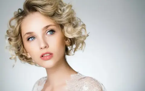 Blondynka z błękitnymi oczami i kręconymi włosami, prezentująca subtelny makijaż smoky eyes.