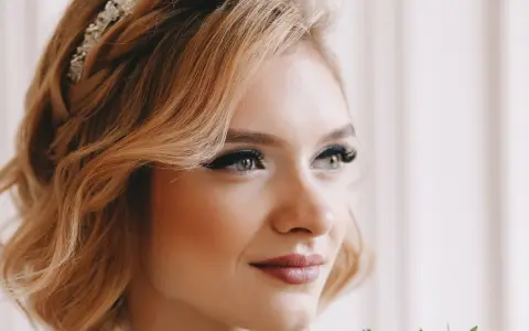 Eleganckie upięcia krótkich włosów na wesele z warkoczem i ozdobą. Delikatne fale i subtelny makijaż podkreślają urodę panny młodej.