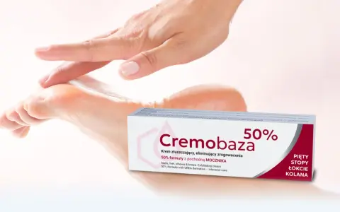 Dłoń delikatnie dotyka stopy, obok opakowanie kremu Cremobaza 50%. Produkt z mocznikiem, który pomaga zwalczać zrogowacenia.