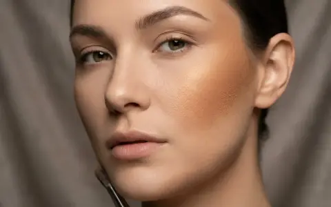 Modelka z ciemnobeżowym bronzerem na policzku, który nadaje jej ciepły, słoneczny wygląd.