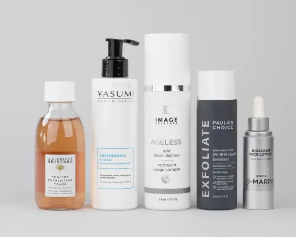 Zestaw kosmetyków do pielęgnacji, w tym tonik z kwasem AHA/PHA, żel z kwasem laktobionowym, cleanser, eksfoliant z kwasem BHA i lotion.