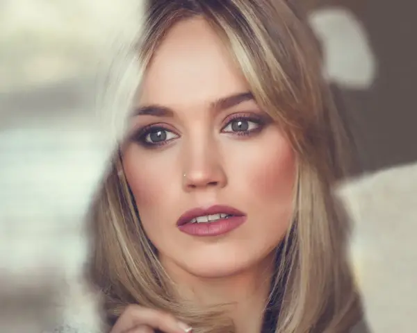 Kobieta z blond włosami i wysokim czołem, patrząca w bok z zamyśleniem.