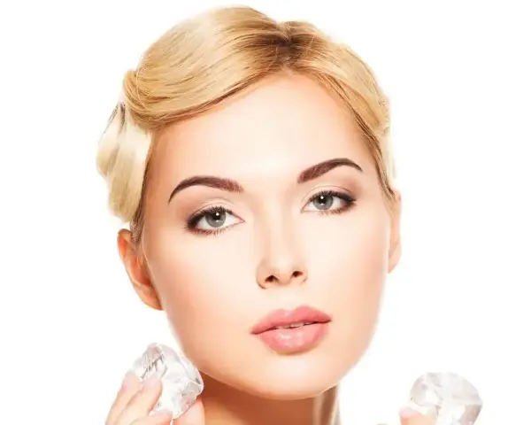 Kobieta z blond włosami stosuje lód na pryszcze, aby uzyskać gładką cerę.