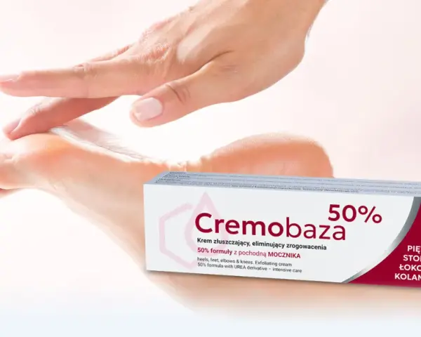 Dłoń delikatnie dotyka stopy, obok opakowanie kremu Cremobaza 50%. Produkt z mocznikiem, który pomaga zwalczać zrogowacenia.