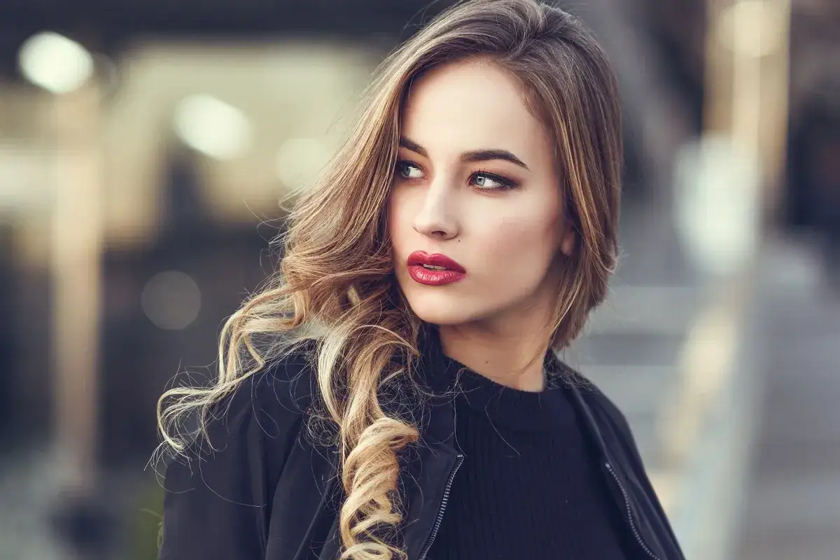 Blondynka w czerni z wyrazistymi, czerwonymi ustami. Idealny kolor pomadki dla blondynek, który podkreśla urodę.